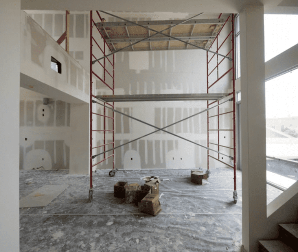 Scaffolding in a living room with high ceilings before painting begins.